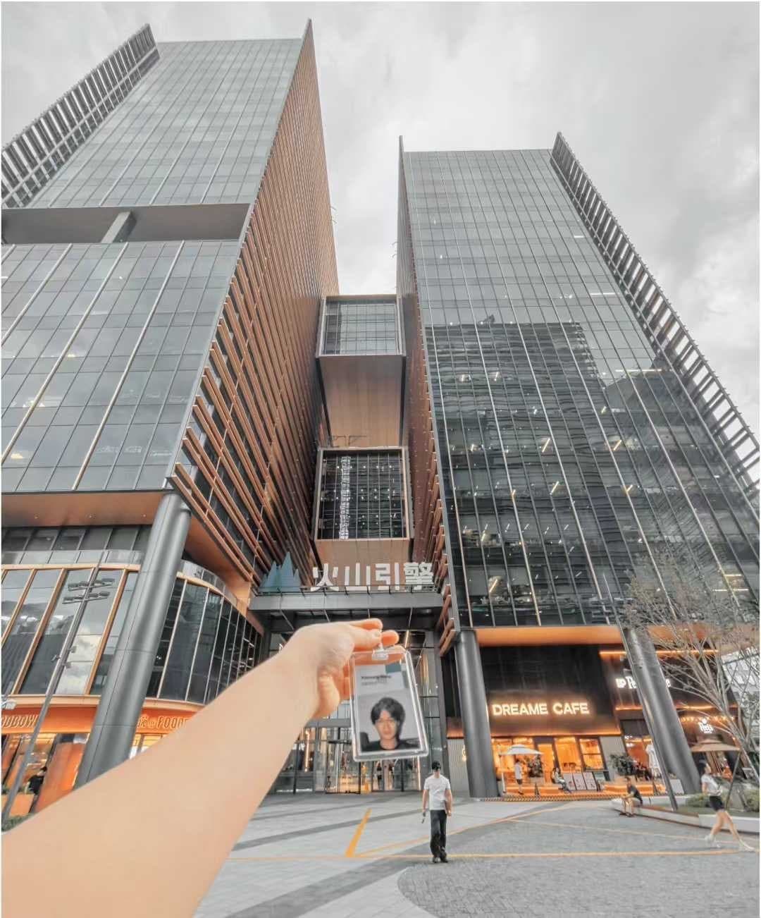 Holding ID badge in front of tall modern office buildings, ByteDance / Volcano Engine