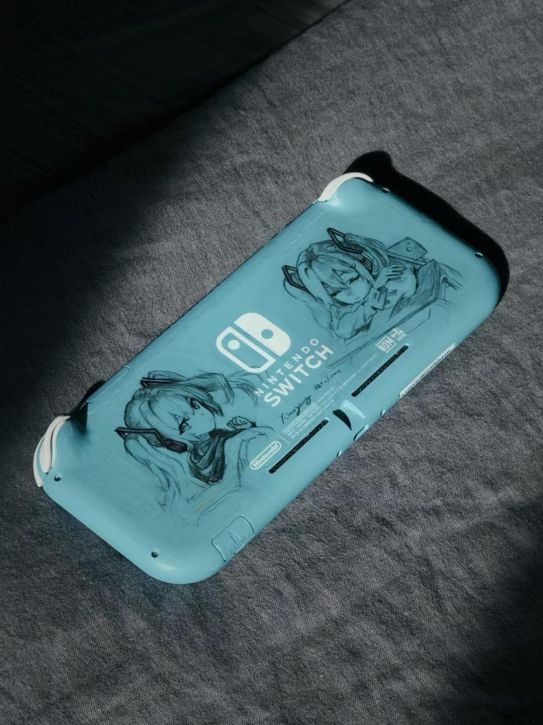 Teal Nintendo Switch Lite with hand-drawn Hatsune Miku in marker on the back