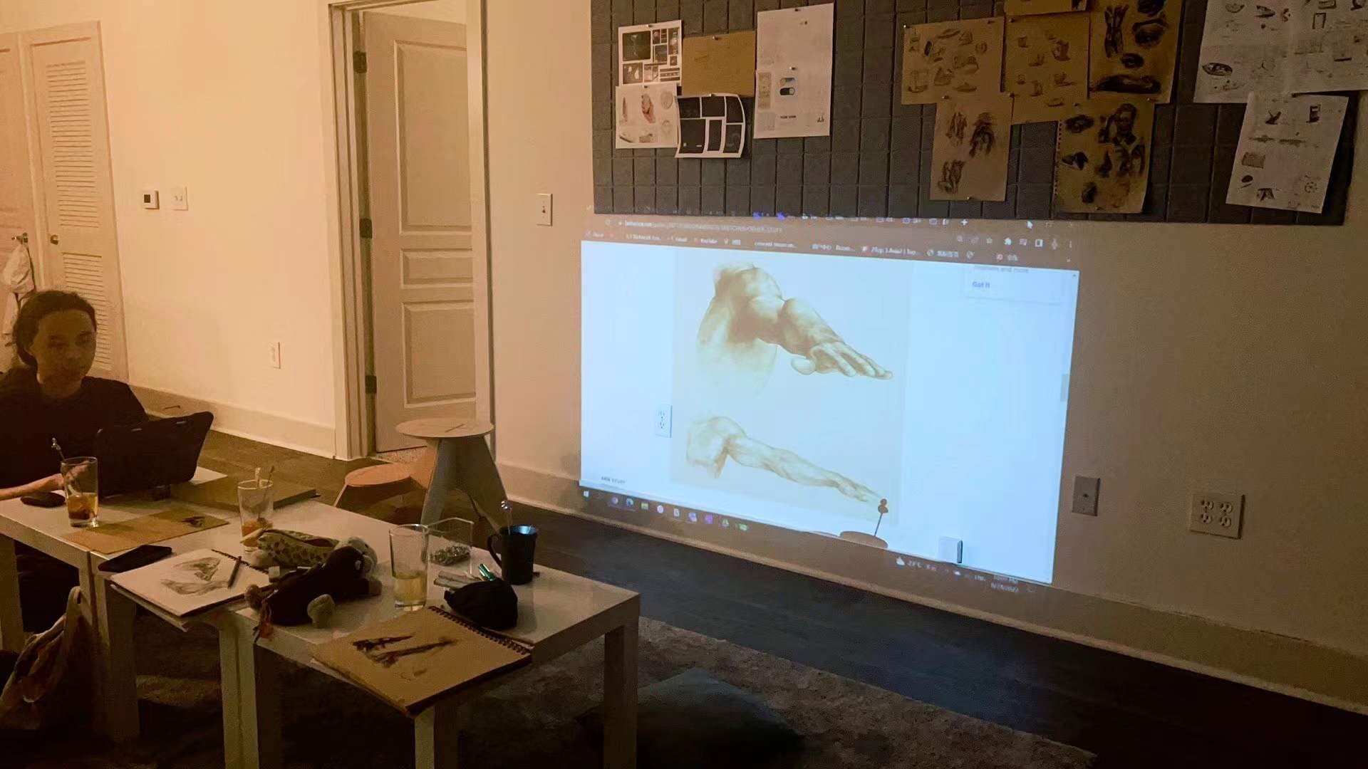Drawing class with laptop and projector showing arm sketch references on the wall