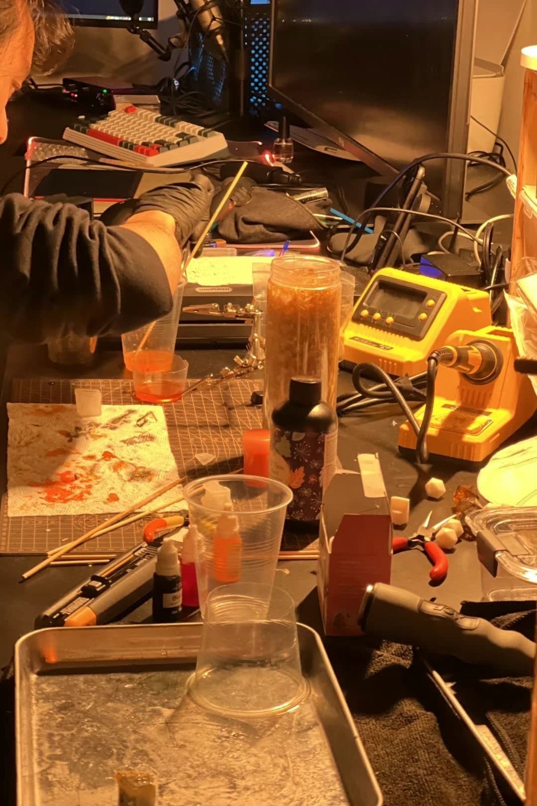 Electronics workbench with soldering iron, microphone, mixed cups and wires