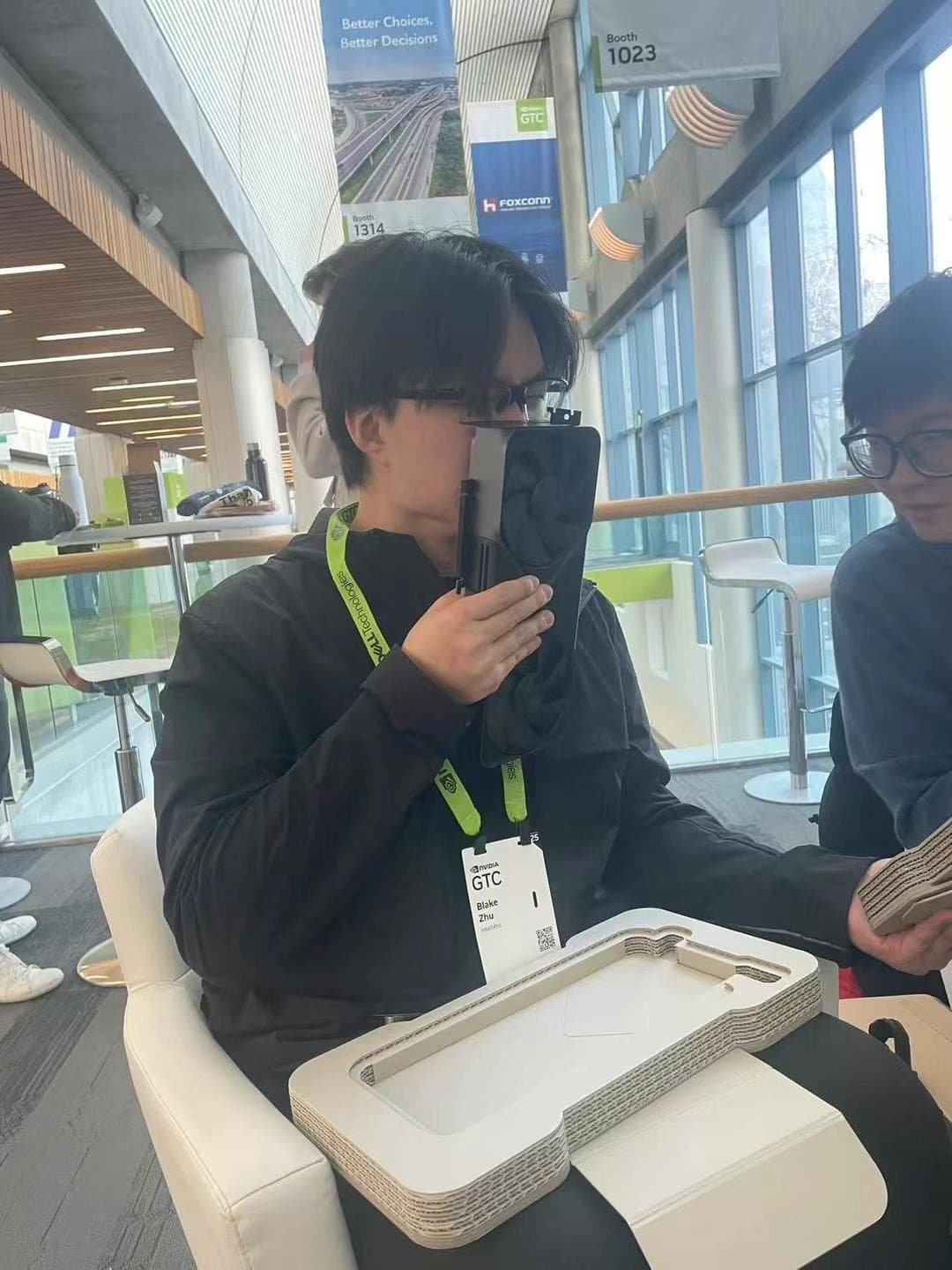 Young man at NVIDIA GTC with conference lanyard, holding a tablet