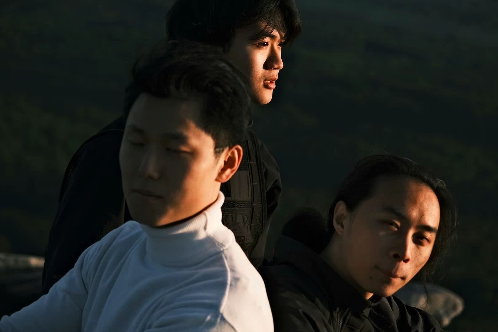 Portrait of three young men in golden-hour light with mountains behind