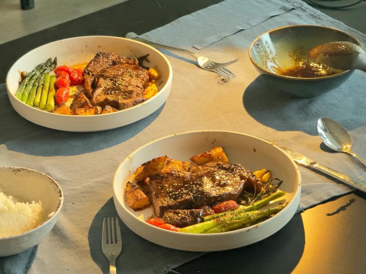 Two plates of steak with asparagus, potatoes, and sauce