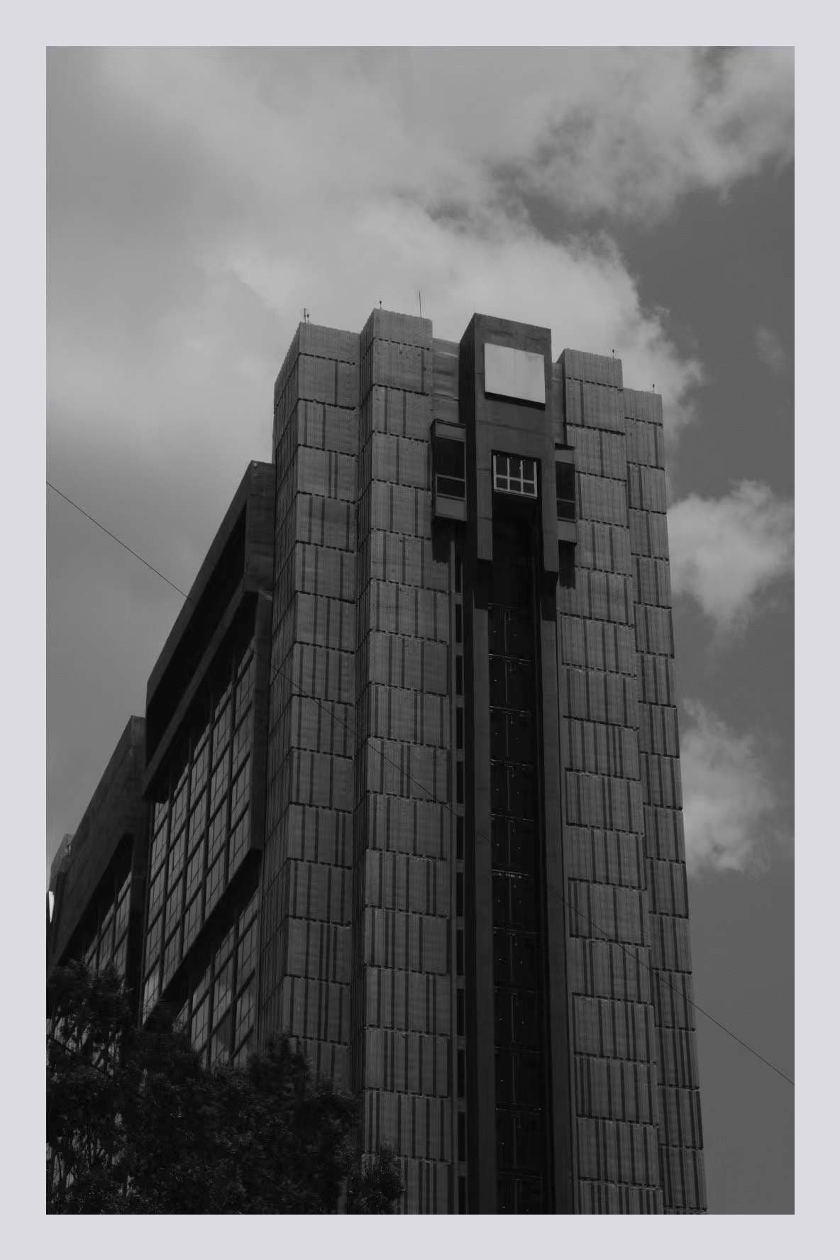 Black-and-white photograph of a brutalist tower against cloudy sky