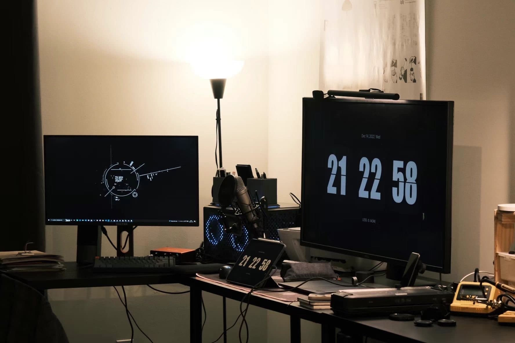 Aspen's desk with dual monitors showing a flip clock and solar system